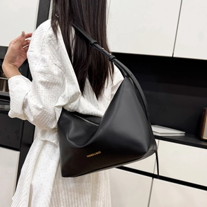 Sac fourre-tout noir minimaliste en forme de croissant porté par un mannequin de profil