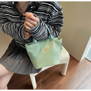 Détail du petit sac en nylon vert menthe étanche avec étiquette mode et zip métallique