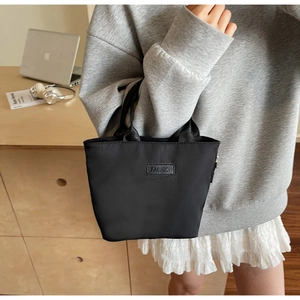 Detail of a minimalist black nylon handbag with fashion label in a daily life setting