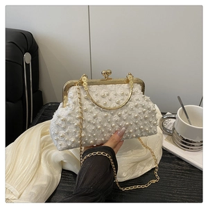 Close-up of white lace crossbody bag with pearl embellishments and gold metal handle