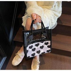Borsa cosmetica trendy in PVC semitrasparente con cuori tenuta da una modella sulle scale