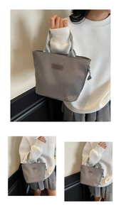 Detail der grauen Nylonhandtasche mit FASHION-Label und robustem silbergrauem Trageband