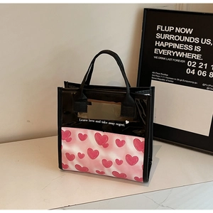 Dettaglio del motivo a cuore rosa e citazione su borsa in PVC nero trasparente