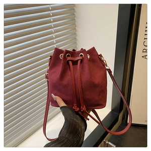 Detail view of burgundy suede bucket bag with drawstring closure and metal eyelets