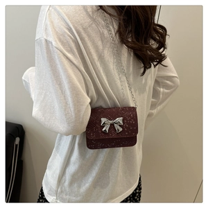 Detailed side view of burgundy snake-pattern mini chain bag with silver bow accent