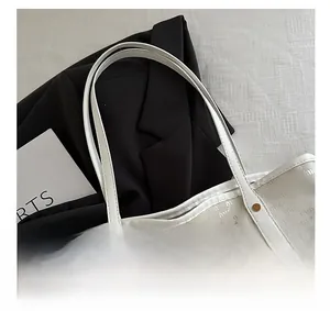 Nahaufnahme der weißen geprägten Leder-Einkaufstasche mit goldenen Nieten-Details