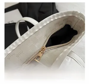 Detailaufnahme des glatten Goldreißverschlusses und Markeninnenfutters der beige Tasche