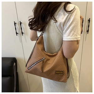 Close-up of brown herringbone hobo bag with diagonal zipper and fashion leather patch