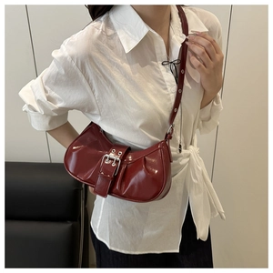 Détail du sac croissant bordeaux en similicuir plissé avec boucle argentée élégante