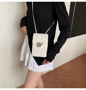 Detail of white quilted mini phone bag with silver bow clasp and leather chain strap