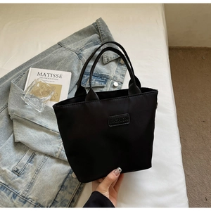 Detail of black nylon tote bag with Fashion leather label and handheld minimalist design