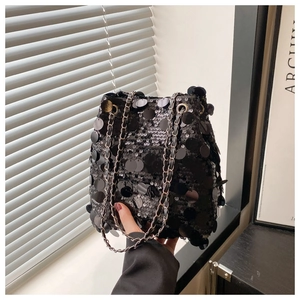 Détail d'un sac seau à paillettes noires avec de grandes écailles et une chaîne argentée