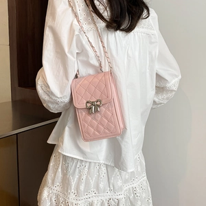 Elegant quilted pink mini phone bag with silver bow clasp and chain strap on model
