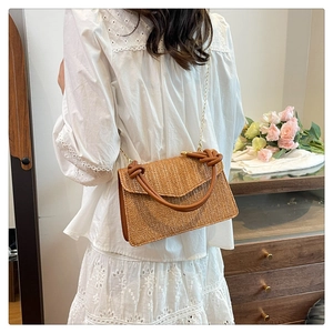 Détail de la texture du sac bandoulière en paille avec poignée cuir et chaîne dorée