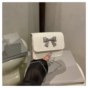 Detalle de mini bolso blanco con textura de serpiente y hebilla de lazo plateada