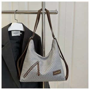 Detalle del bolso tote con diseño de espiga en blanco y negro con correas de cuero marrón
