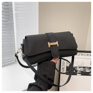 Close-up of black Saffiano leather texture and golden H-shaped buckle detail on handbag