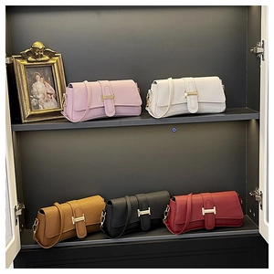 Row of leather underarm bags in five colors with golden metallic buckles on display