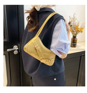 Detail of light gold crocodile embossed underarm bag with buckle and rivet hardware