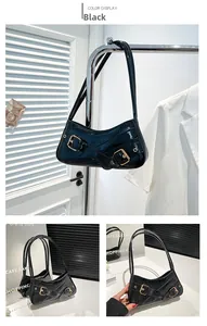 Detail of black glossy crocodile pattern shoulder bag with golden decorative buckles
