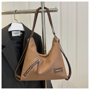 Detalle de bolso tote de tejido marrón con bolsillo frontal con cremallera y asas largas