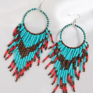 Bohemian tassel hoop earrings with turquoise and red beads on white satin fabric