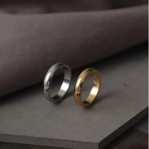 Minimalist gold and silver polished stainless steel bands on a textured dark board