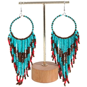 Bohemian seed bead hoop earrings with colorful turquoise and red fringe on a gold stand