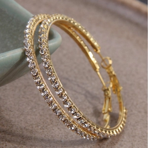 Pair of elegant 5.0cm gold hoop earrings with pavé set crystals on a ceramic surface