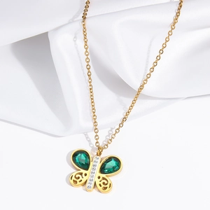 Vue macro du pendentif papillon doré avec gemmes vertes et détails en zircon