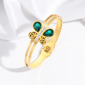 Détail d'un bracelet papillon doré orné de pierres vertes et de zircons étincelants