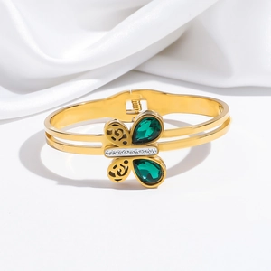 Gros plan du bracelet doré avec ailes de papillon vert émeraude et détails en cristal