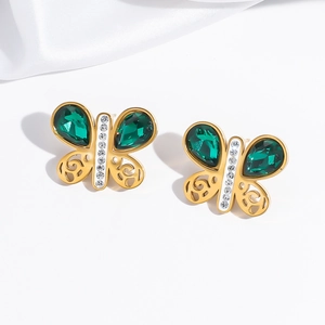 Détail de boucles d'oreilles papillon dorées avec pierres vert émeraude taille poire