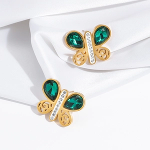 Détail macro de boucles d'oreilles papillon dorées avec pierres émeraude et cristaux