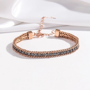 Macro view of rose gold double-row woven chain bracelet with black zircon stones
