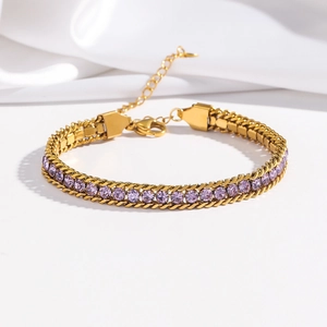 Detail of a gold-plated double-chain bracelet with purple zircon inlay on white satin