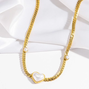Détail du collier chaîne gourmette dorée avec pendentif perle en cœur et charmes rétro