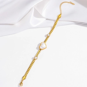 Détail d'un bracelet doré en maille serpent avec perle en cœur et fermoir mousqueton