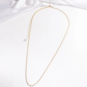 Detailed close-up of a long gold snake chain necklace featuring a white pearl pendant
