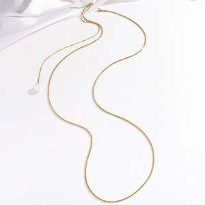Minimalist gold snake chain necklace featuring a baroque pearl pendant on silk background