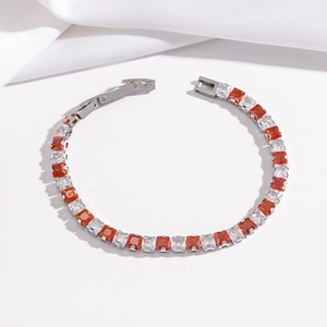 Bracelet tennis ajustable avec zircons orange et blancs sur un fond de soie blanche