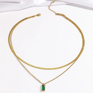 Detail view of double-layer gold snake chain necklace with emerald green zircon pendant