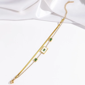 Close-up of gold double-layer chain bracelet with green zircon and white enamel pendant