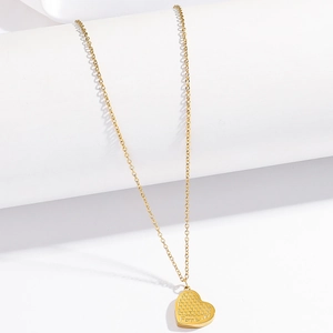 Detail of a gold heart pendant with honeycomb texture and Forever engraving