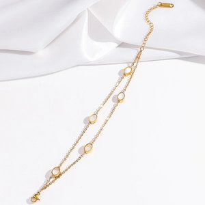 Detail of double-layer gold chain bracelet featuring white shell inserts and lobster clasp