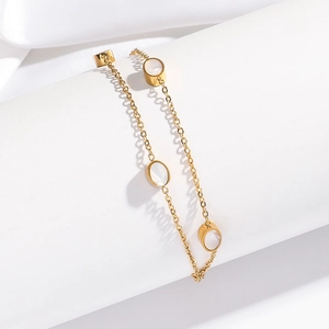 Macro detail of a gold chain bracelet featuring three elegant oval mother of pearl shells