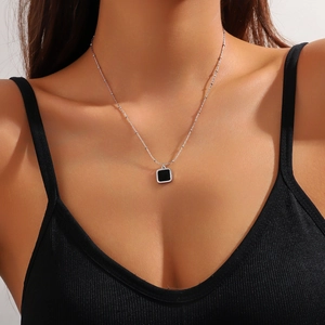 Close-up of minimalist square black pendant with silver satellite chain on neck