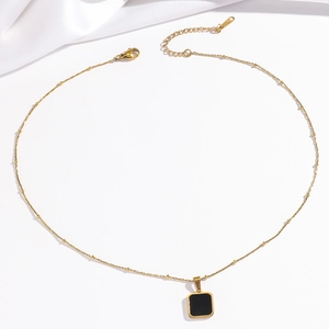Detail of gold stainless steel beaded chain with square black pendant and lobster clasp