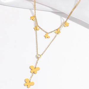 Détail d'un collier papillon double couche doré avec une pierre centrale en forme de coeur