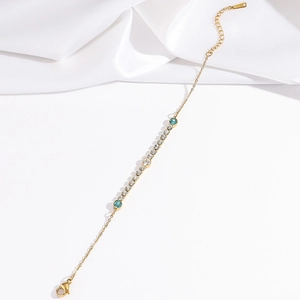 Detail of gold chain bracelet featuring white crystals and blue rhinestones on silk